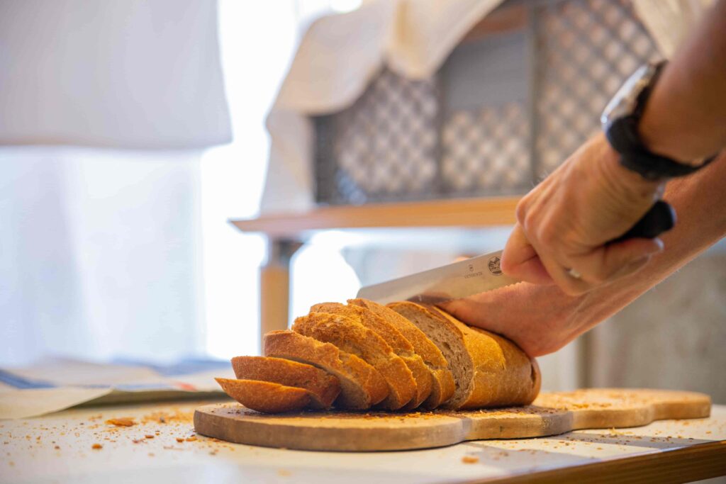 Brot das von jemandem in Scheiben geschnitten wird