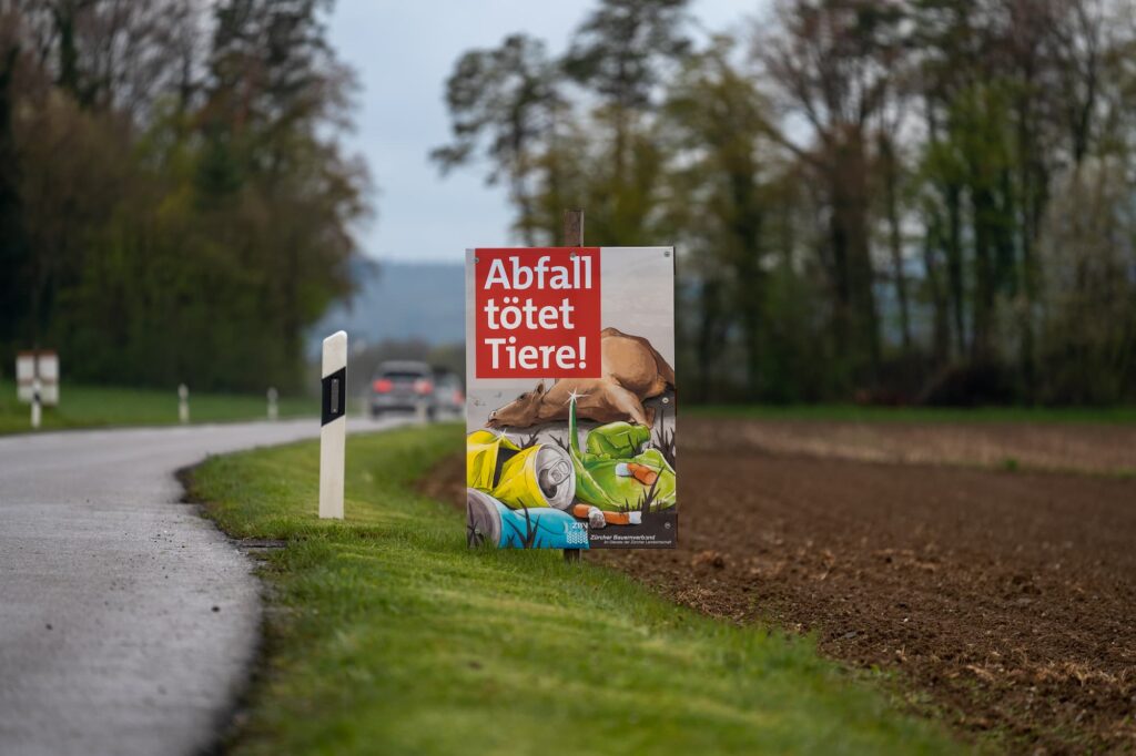 Ein Schild mit der Aufschrift "Abfall tötet Tiere" an einem Strassenrand.