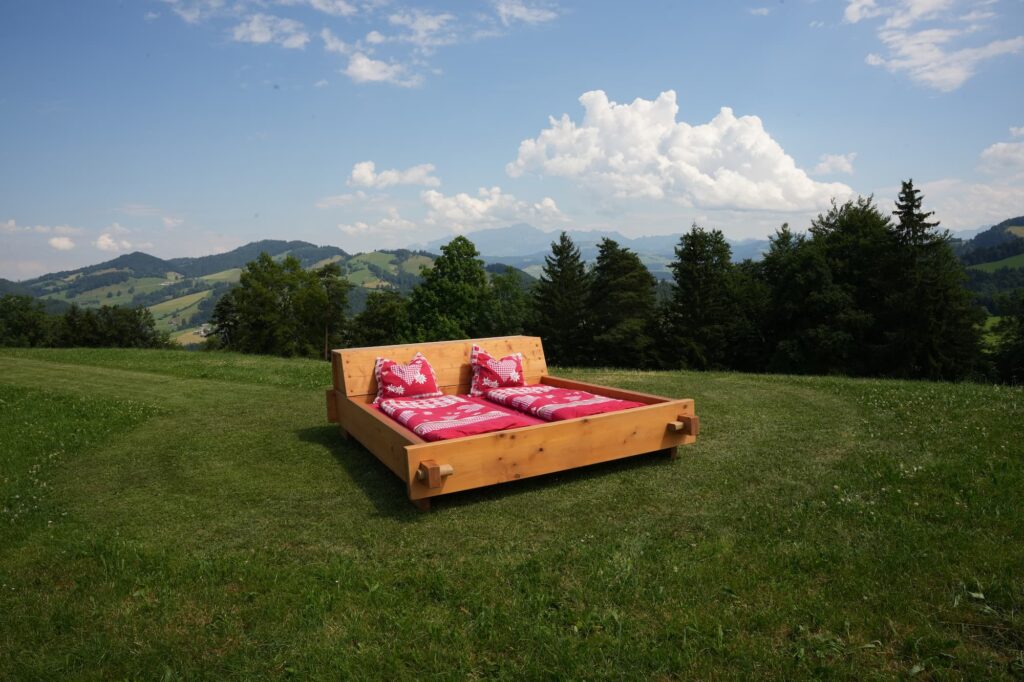 Ein Bett mit roter Bettwäsche unter freiem Himmel.